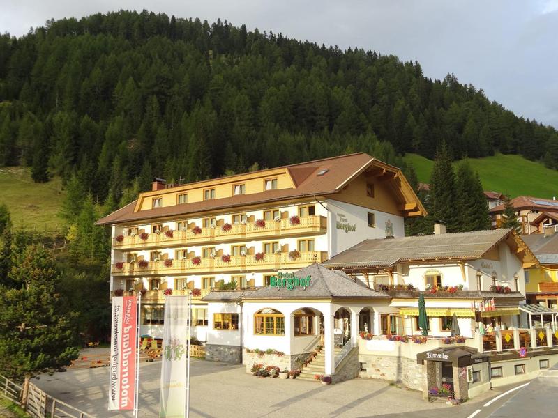 Large traditional hotel with wooden balconies in front of a forested hill