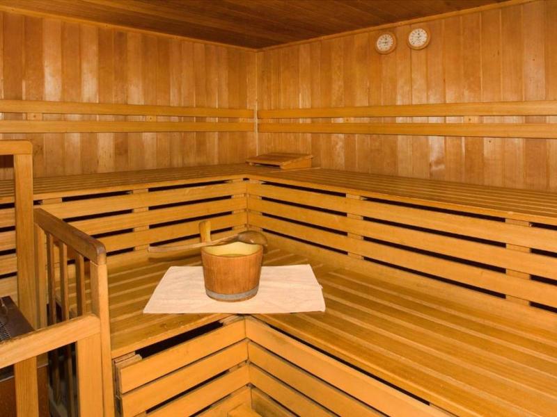 Wooden sauna with multi-tiered benches and a wooden bucket on a towel in the corner