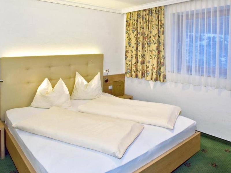 Cozy hotel room with a double bed, curtains, and carpeted floor.