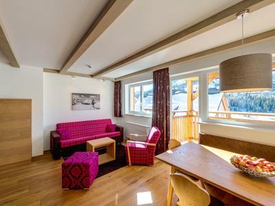 Modern hotelkamer met zithoek en groot raam met uitzicht op bergen.