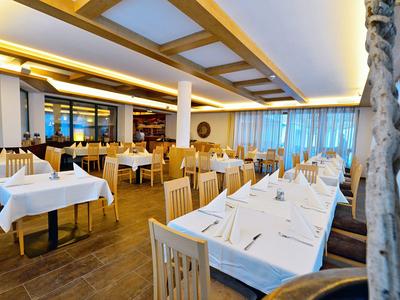 Restaurante elegante con manteles blancos y sillas de madera, iluminado cálidamente y decorado modernamente.