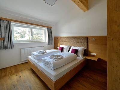 Moderne slaapkamer met tweepersoonsbed, houten vloer en raam met gordijnen.