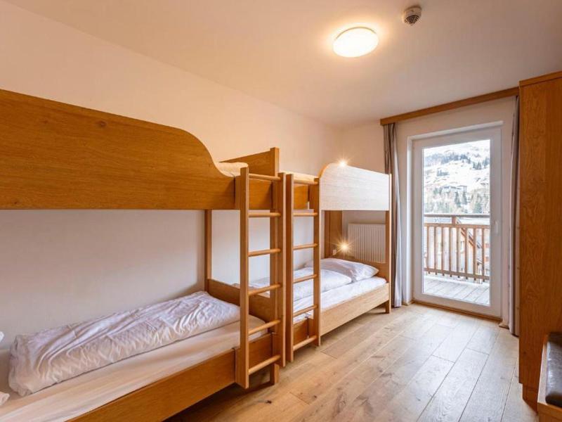 Een kamer met twee houten stapelbedden, balkon en lichte houten meubels.