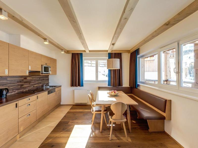Lichte moderne keuken in vakantiewoning met houten fronten, eethoek en grote ramen.