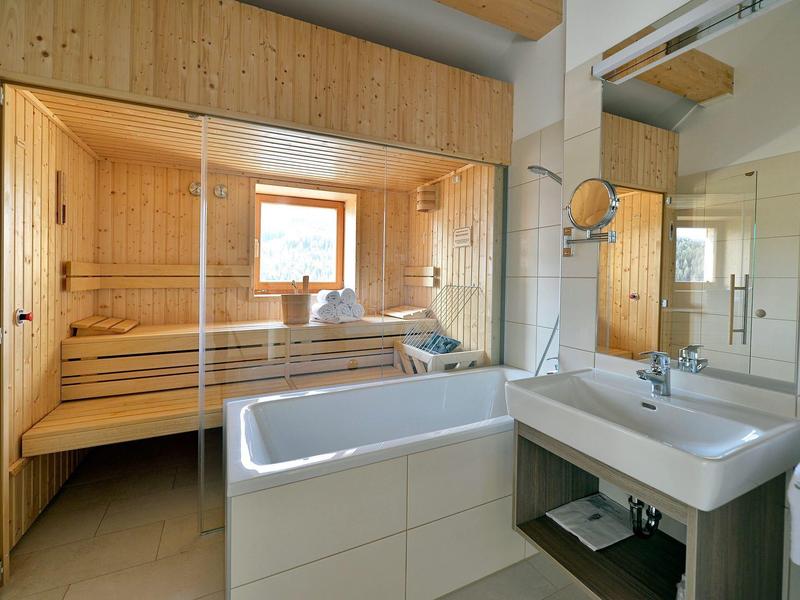 Moderne badkamerinrichting met douche, wastafel en aangrenzende houten sauna