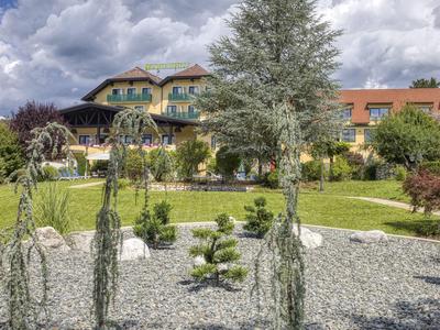Hotel mit Garten, Kiesbeeten und dekorativen Pflanzen unter bewölktem Himmel.