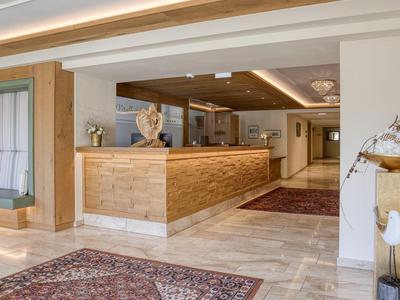 Helle Hotellobby mit Holzelementen, Teppichen und modernem Empfangstresen.