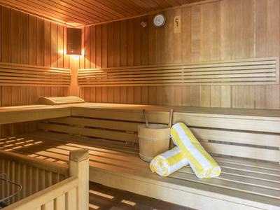 Sauna mit Holzbänken, Wandelementen und zwei gelb-weißen Handtüchern.