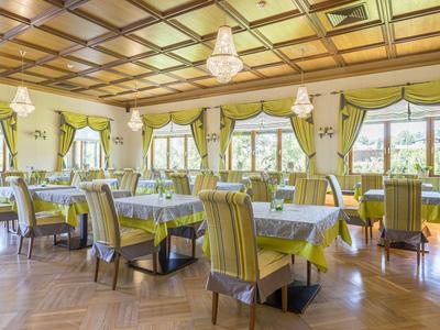 Eleganter Speiseraum mit Holzdecke, großen Fenstern und grün-gelb gestreiften Stühlen.