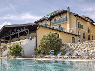 Moderner Hotelkomplex mit Außenpool, Liegestühlen und klarem Himmel.