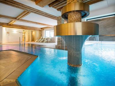 Modern indoor pool with blue water and a gold central water feature