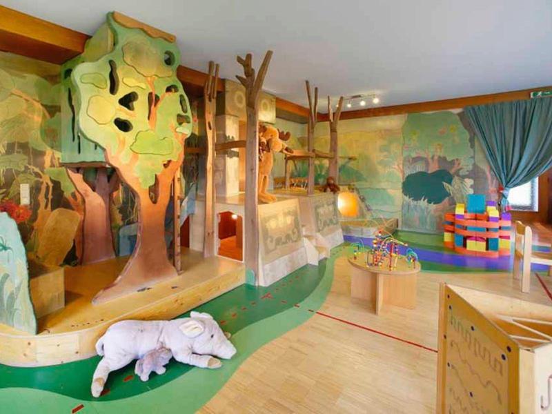 Children's play area with climbing frame, stuffed animal, and colorful blocks in a bright room.