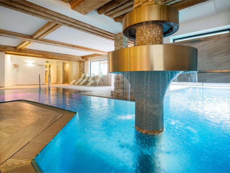 Modern indoor pool with blue water and a gold central water feature