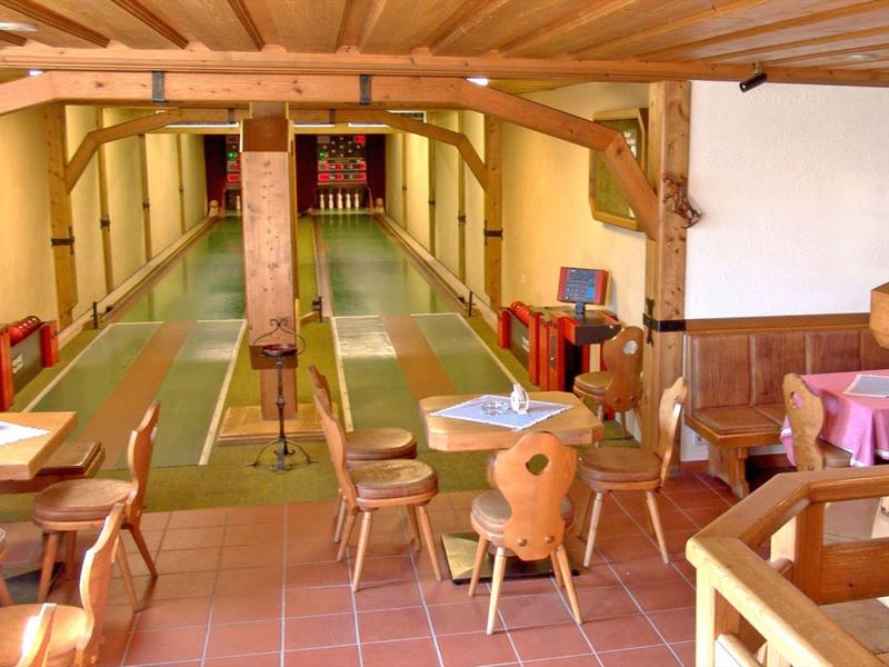Accogliente sala per il gioco delle bocce con tavoli, sedie e soffitto con travi in legno.