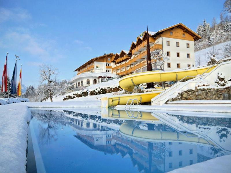 Hotel con piscina e scivolo d'acqua in un paesaggio invernale innevato.