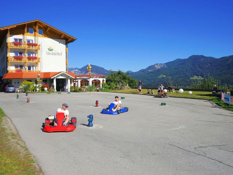 Bambini che corrono sulla strada davanti a un hotel con sfondo montano.