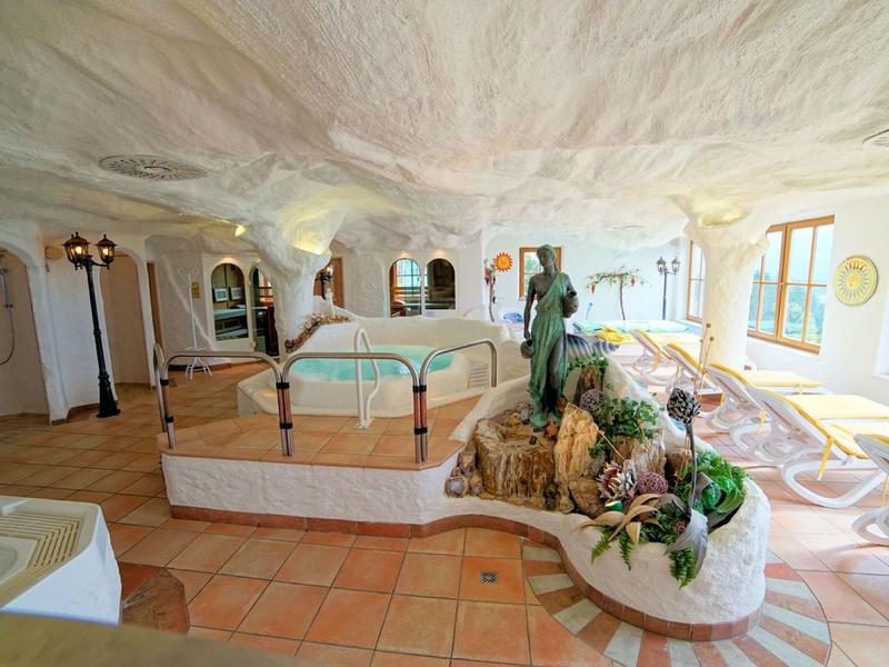 Area benessere luminosa con vasca idromassaggio, piante e grandi finestre per molta luce naturale.