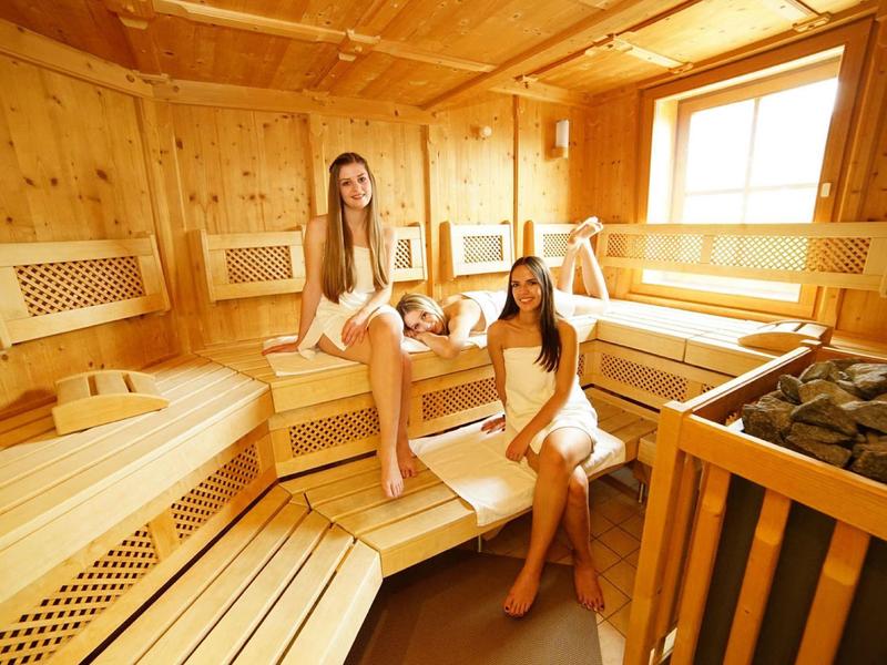 Interno di una sauna in legno con due donne avvolte in asciugamani che si rilassano.