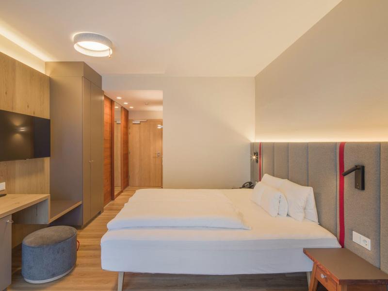 Chambre d'hôtel moderne avec deux lits simples, mobilier en bois et éclairage doux.