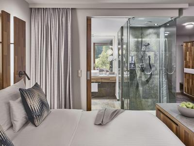 Camera d'hotel moderna con letto king size, doccia in vetro e luce naturale