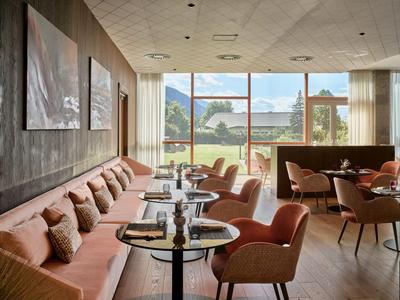 Modernes Hotelrestaurant mit großen Fenstern und Blick auf Berge und See.