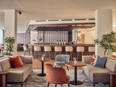 Modern eingerichtete Hotellounge mit Bar, Sesseln und Sofas in warmen Farben.