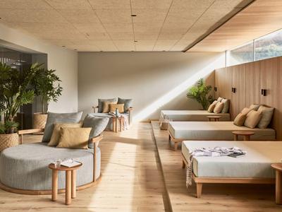 Helles, modernes Hotelzimmer mit Holzakzenten, Sitzbereich und Tagesbetten.