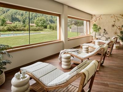 Eleganter Ruheraum mit Holzliegen und Aussicht auf grüne Landschaft und Fluss.