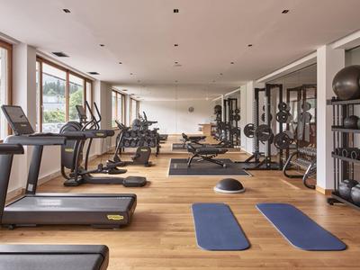 Heller Fitnessraum mit modernen Geräten, Yogamatten und Holzfußboden im Hotel.