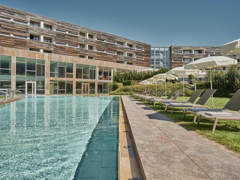 Nowoczesny zewnętrzny basen hotelowy z leżakami i dużymi parasolami pod czystym niebem.