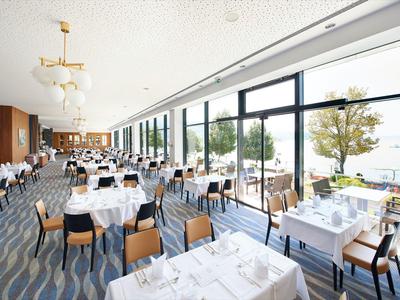 Ampia e luminosa sala da pranzo con grandi finestre e tavoli apparecchiati per gli ospiti.