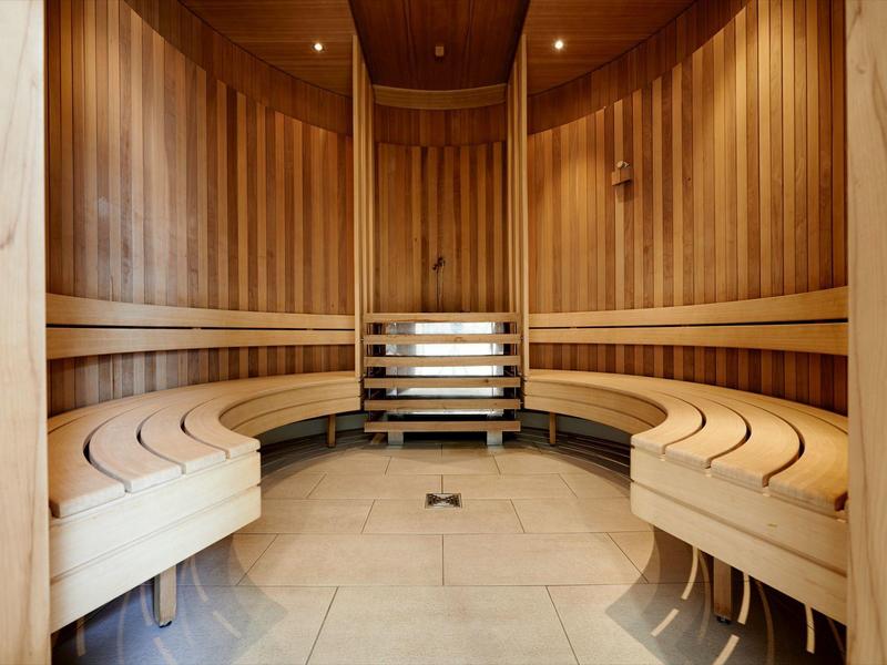 Sauna ben illuminata con pannelli in legno e panchine a semicerchio.