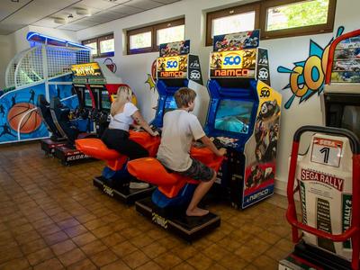 Due persone giocano a giochi arcade di scooter in una stanza con un gioco arcade di basket.