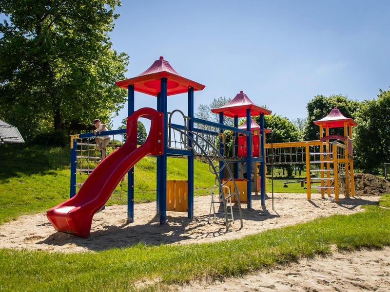 Kleurrijke kinderspeeltuin met glijbanen en klimrekken in een zonnig park.