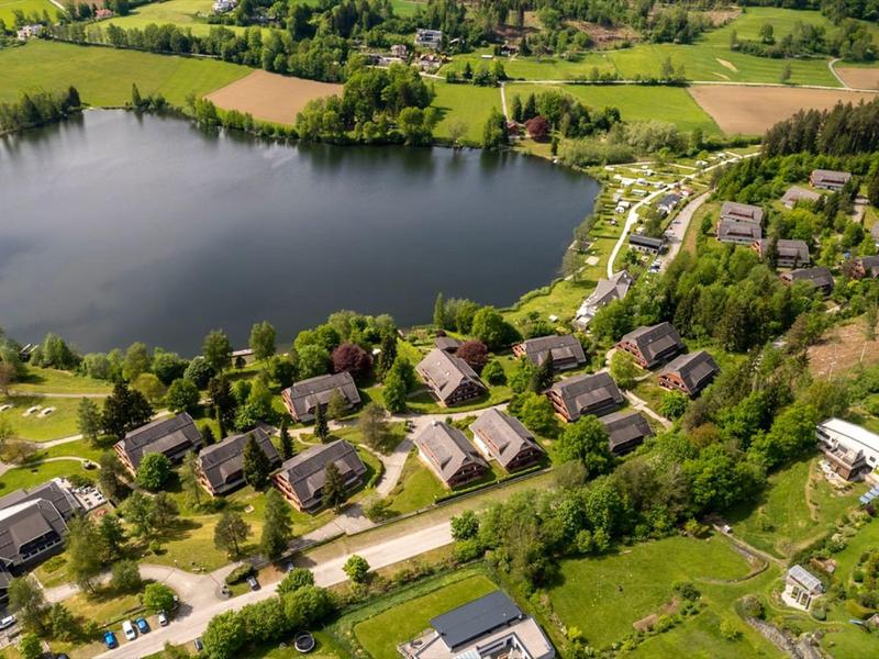 Luchtfoto van een klein dorp met huizen aan een meer en groene omgeving.