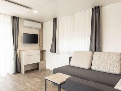 Sala moderna con sofá, mesa de centro y televisor montado en la pared en un espacio luminoso.