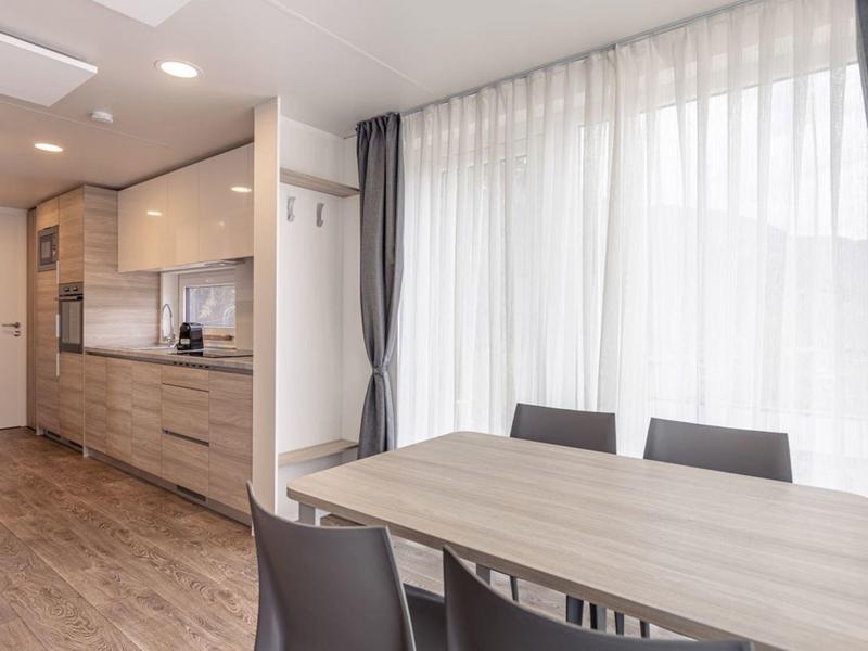 Moderner Essbereich mit Holztisch, schwarzen Stühlen und großer Fensterfront mit weißen Vorhängen.