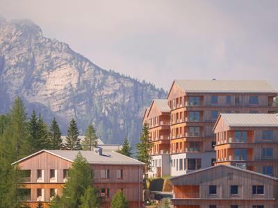 Mehrere Hotelgebäude aus Holz vor einem bewaldeten Berg mit Felsen
