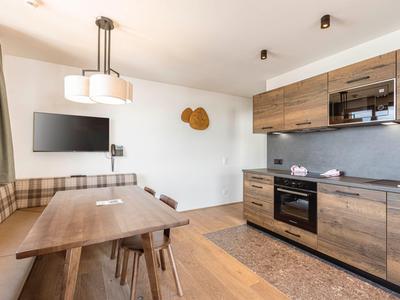 Moderner Küchen- und Essbereich mit Holzmöbeln und wandmontiertem Fernseher.