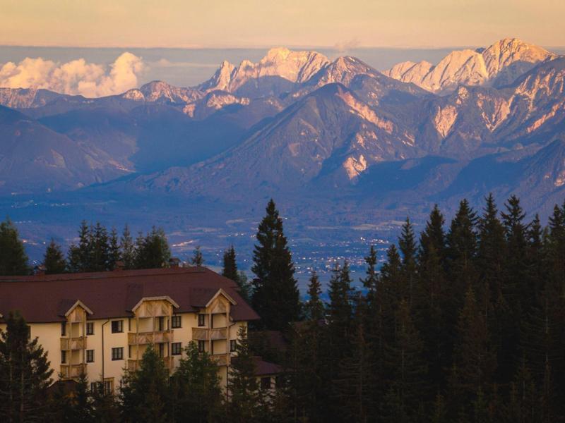 Mountain hotel with snow-capped peaks in the background and forest in the foreground