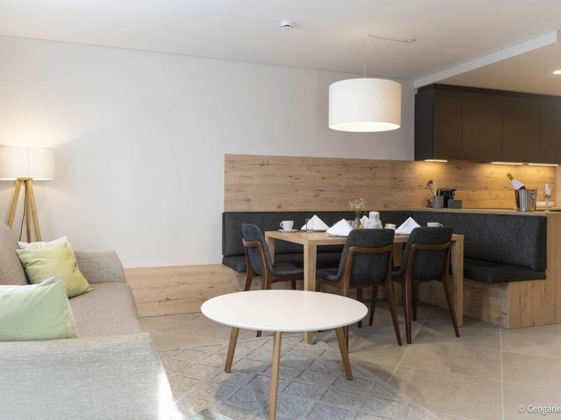 Modern living room with sofa, round table, and dining table in a hotel room