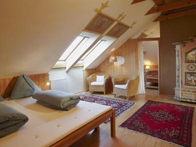 Acogedora habitación en el ático con muebles de madera, dos camas, sillas y alfombras bajo ventanas de techo.