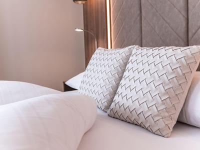Zwei Kissen mit Zickzackmuster auf einem weißen Bett in einem Hotelzimmer.