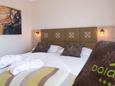 Modern eingerichtetes Hotelzimmer mit großem Bett, weichen Kissen und stilvollen Wandlampen.