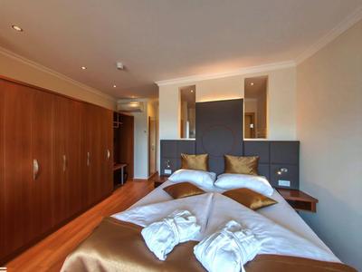 Modernes Hotelzimmer mit Doppelbett, Holzmöbeln und zwei Bademänteln auf der Bettdecke.