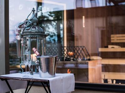 Elegante Außenterrasse mit einem Tisch, dekorativer Laterne und Blick auf eine Sauna.