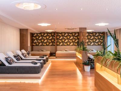 Moderner Ruheraum mit Liegen, Holzboden und Pflanzen, ideal für Hotelgäste zum Entspannen.