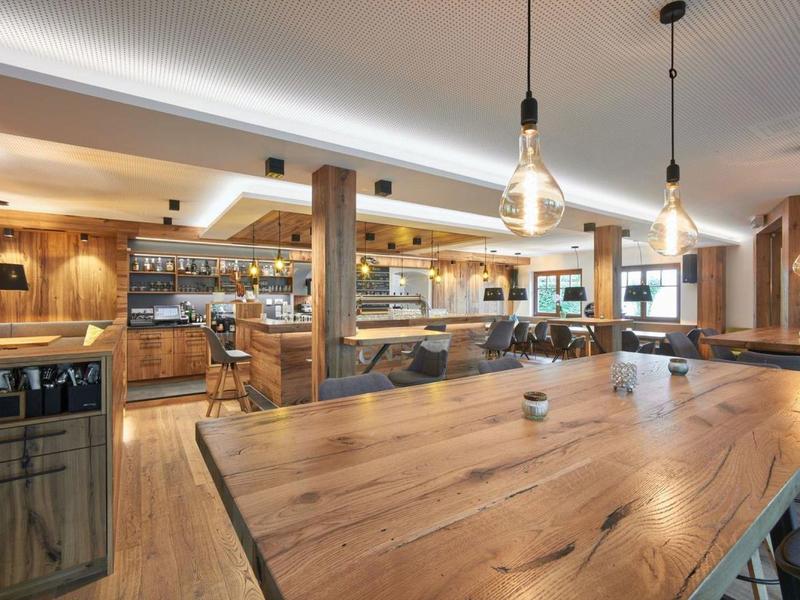 Moderne hotelbar en restaurant met houten meubels en sfeerverlichting.