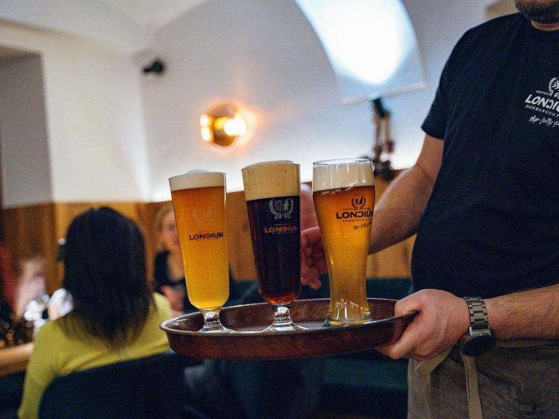 Kelner draagt een dienblad met vier glazen bier in een bar of restaurant.