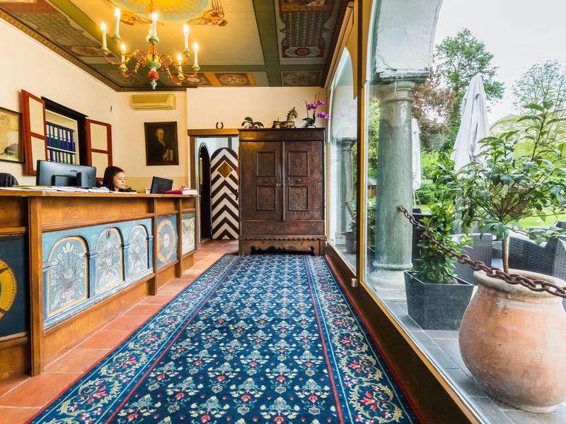 Helle Diele mit blumenmusterte Teppich, großen Fenstern und antikem Holzschrank.